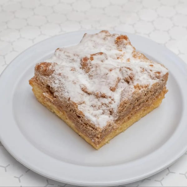 A square slice of Sunshine Grill's coffee cake with a crumbly topping and powdered sugar.